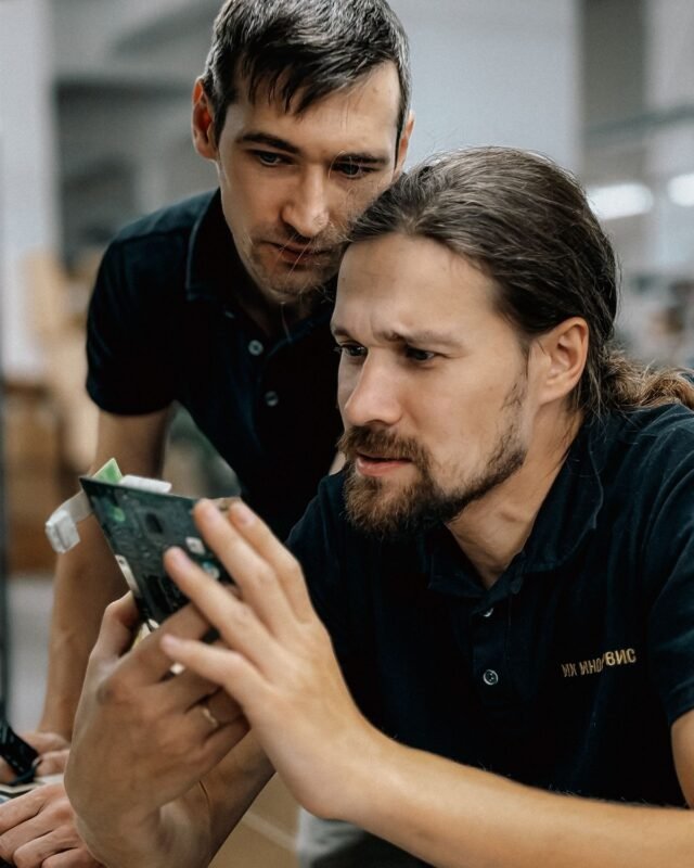 Two engineers reviewing a PCBA during production coordination